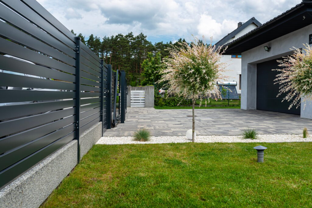 A modern panel fence in anthracite color, visible sliding gate to the garage and a garbage place