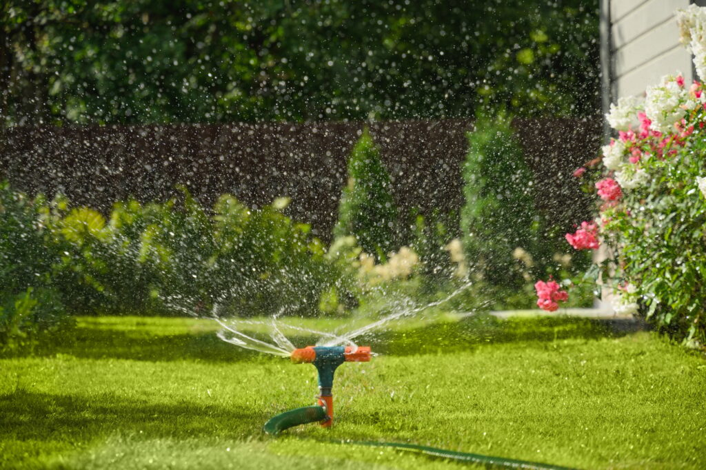 Automatic smart irrigation system. Watering garden with hose on backyard.